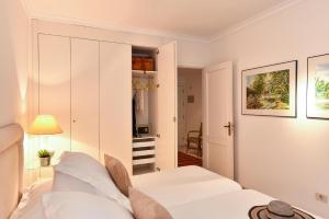 Las Canteras Seafront Apartment في لاس بالماس دي غران كاناريا: غرفة نوم بيضاء مع سرير وخزانة