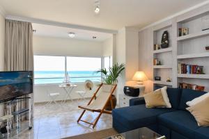 Las Canteras Seafront Apartment في لاس بالماس دي غران كاناريا: غرفة معيشة مع أريكة زرقاء وإطلالة على المحيط