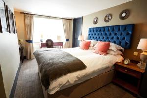 a bedroom with a large bed with a blue headboard at The Fleece at Cirencester in Cirencester