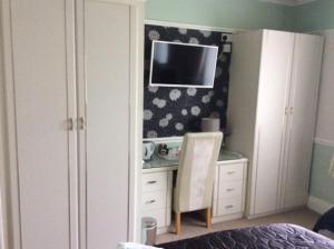 um quarto com uma secretária e uma televisão na parede em Alma Lodge Guest House em Plymouth