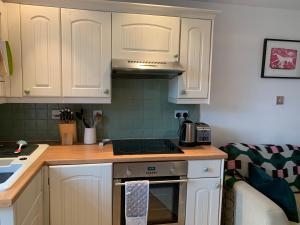 La cuisine est équipée de placards blancs et d'un four avec plaques de cuisson. dans l'établissement Weaver's Cottage @ Number 10, à Bradford-on-Avon