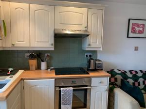 a kitchen with white cabinets and a stove top oven at Weaver's Cottage @ Number 10 in Bradford on Avon