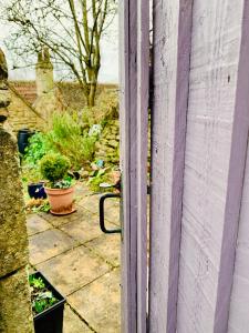 an open door to a garden with potted plants at Weaver's Cottage @ Number 10 in Bradford on Avon