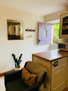 a kitchen with a chair and a counter and a microwave at Weaver's Cottage @ Number 10 in Bradford on Avon