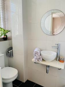 a white bathroom with a sink and a mirror at Weaver's Cottage @ Number 10 in Bradford on Avon