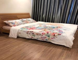 ein Bett mit einer weißen Decke mit Blumen drauf in der Unterkunft Capitalland's Service Apartment Park 5 Vinhomes in Ho-Chi-Minh-Stadt