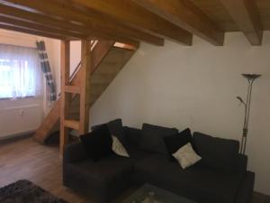 een woonkamer met een zwarte bank en een houten trap bij Holidayapartment Rüsselsheim in Rüsselsheim