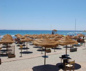 Ein Haufen Strohschirme am Strand in der Unterkunft Corallo Vacanze in Villaputzu