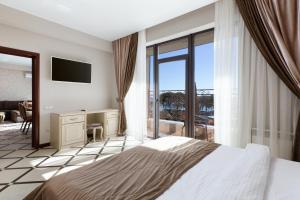 een slaapkamer met een bed, een bureau en een balkon bij MODART Olympic Hotel & Beach in Adler