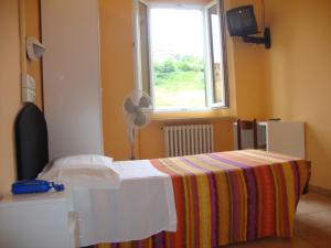 a room with a bed and a window and a fan at Albergo Gino in Ancona