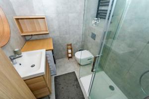 a bathroom with a shower and a sink and a toilet at Sand - Neptun Park by OneApartments in Gdańsk