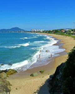 a group of people on a beach with the ocean at Apto Completo Praia Central Armação in Penha