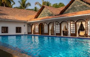 a swimming pool in front of a house at The Postcard Cuelim, Goa in Utorda