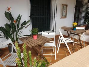 un patio con 2 mesas, sillas y macetas en Alojamiento Rural Flamingo, en El Rocío