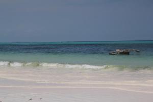 ein Boot, das im Wasser am Strand schwimmt in der Unterkunft Tamani Villas in Matemwe