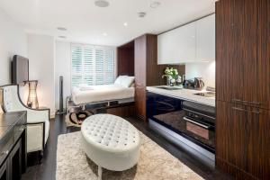 uma cozinha com uma cama e um banco num quarto em ALTIDO Luxury Studio in Chelsea, close to Sloane Square and Victoria station em Londres