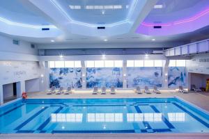 a large swimming pool with chairs and a large pool at Falenty Biznes i Wypoczynek in Raszyn