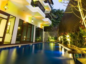 a swimming pool in front of a house at night at Baan Ratchiangsaen in Chiang Mai