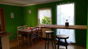 cocina con paredes verdes, mesa y sillas en Ferienhaus grüne Oase en Halle an der Saale