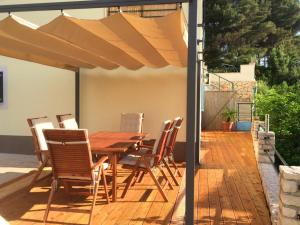 a wooden table and chairs under an umbrella on a deck at Eco Sunshine Apartments Lumbarda in Lumbarda