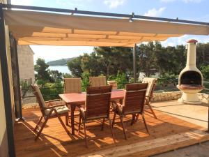 a wooden table and chairs on a wooden deck at Eco Sunshine Apartments Lumbarda in Lumbarda