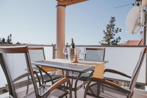 a table and chairs on a balcony with a bottle of wine at Poolside Hideout Apartments in Novalja