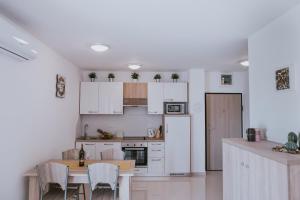 a kitchen with white cabinets and a table with chairs at Poolside Hideout Apartments in Novalja
