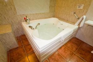 a white bath tub in a tiled bathroom at Hostal Nueva Andalucia in Alcalá de Guadaira