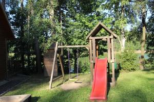 un parque infantil en un patio con un tobogán rojo en Domki nad jeziorem w Karłowicach, en Karłowice