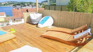 a wooden deck with a bench and pillows on it at Eco Sunshine Apartments Lumbarda in Lumbarda