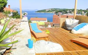 a wooden deck with chairs and a view of the water at Eco Sunshine Apartments Lumbarda in Lumbarda