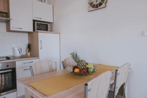 a kitchen with a table with a bowl of fruit on it at Poolside Hideout Apartments in Novalja