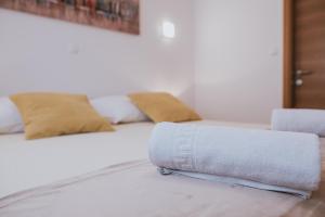 a white bed with two pillows and a towel at Poolside Hideout Apartments in Novalja