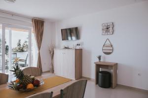 a dining room with a table with a bowl of fruit on it at Poolside Hideout Apartments in Novalja