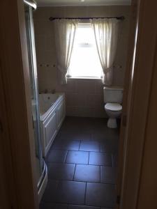 uma casa de banho com uma banheira, um WC e uma janela. em Springfield Holiday Home em Carndonagh