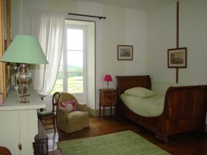 een slaapkamer met een bed, een stoel en een raam bij Masbareau, Demeure de Charme, B&B in Royères-Saint-Léonard