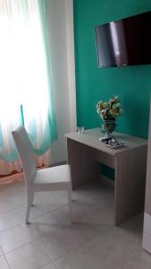 einen Schreibtisch mit einem Stuhl und einer Vase mit Blumen darauf in der Unterkunft B&B Romy in Tropea