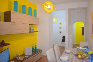 ein Esszimmer mit einem Tisch und einer gelben Wand in der Unterkunft Red & Blu Apartments in Desenzano del Garda