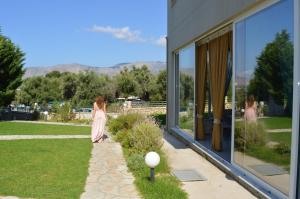 a woman walking down a sidewalk next to a building at Thesmos Village in Mitika