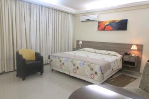 a hotel room with a bed and a chair at Apart Hotel Acrópolis in Santana do Livramento