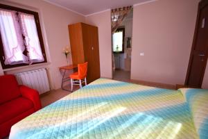 1 dormitorio con 1 cama y 1 silla roja en B&b La Nuova Stella, en Perano