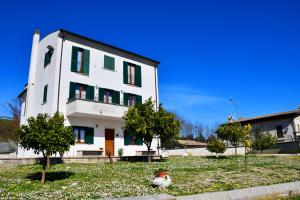 a white house with green shutters and a tree at B&b La Nuova Stella in Perano