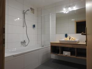 a bathroom with a tub and a sink and a mirror at Hotel Tauernglöckl in Obertauern