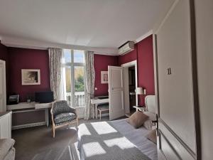 um quarto com paredes vermelhas, uma cama e uma secretária em Hôtel du Parc em Montpellier
