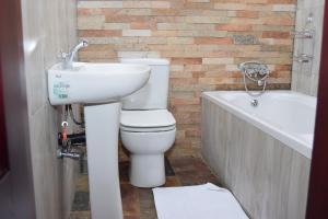 a bathroom with a toilet and a sink and a bath tub at Upland Estates Serviced Apartments in Lusaka +26 photos