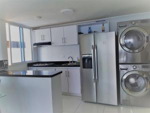 una cocina con armarios blancos y electrodomésticos de acero inoxidable en Espectaculares Vistas, Edificio Nautilus, Barrio El Laguito., en Cartagena de Indias