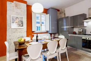 cocina con mesa de madera y sillas blancas en Borgo Suite, en Pisa