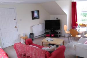 a living room with a red couch and a tv at The Garden Apartment in Dunino