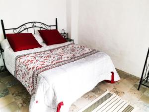 a bedroom with a bed with red pillows at Ojalá... in Vejer de la Frontera