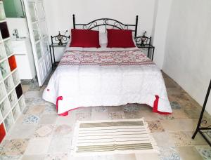 a bedroom with a large bed with red pillows at Ojalá... in Vejer de la Frontera